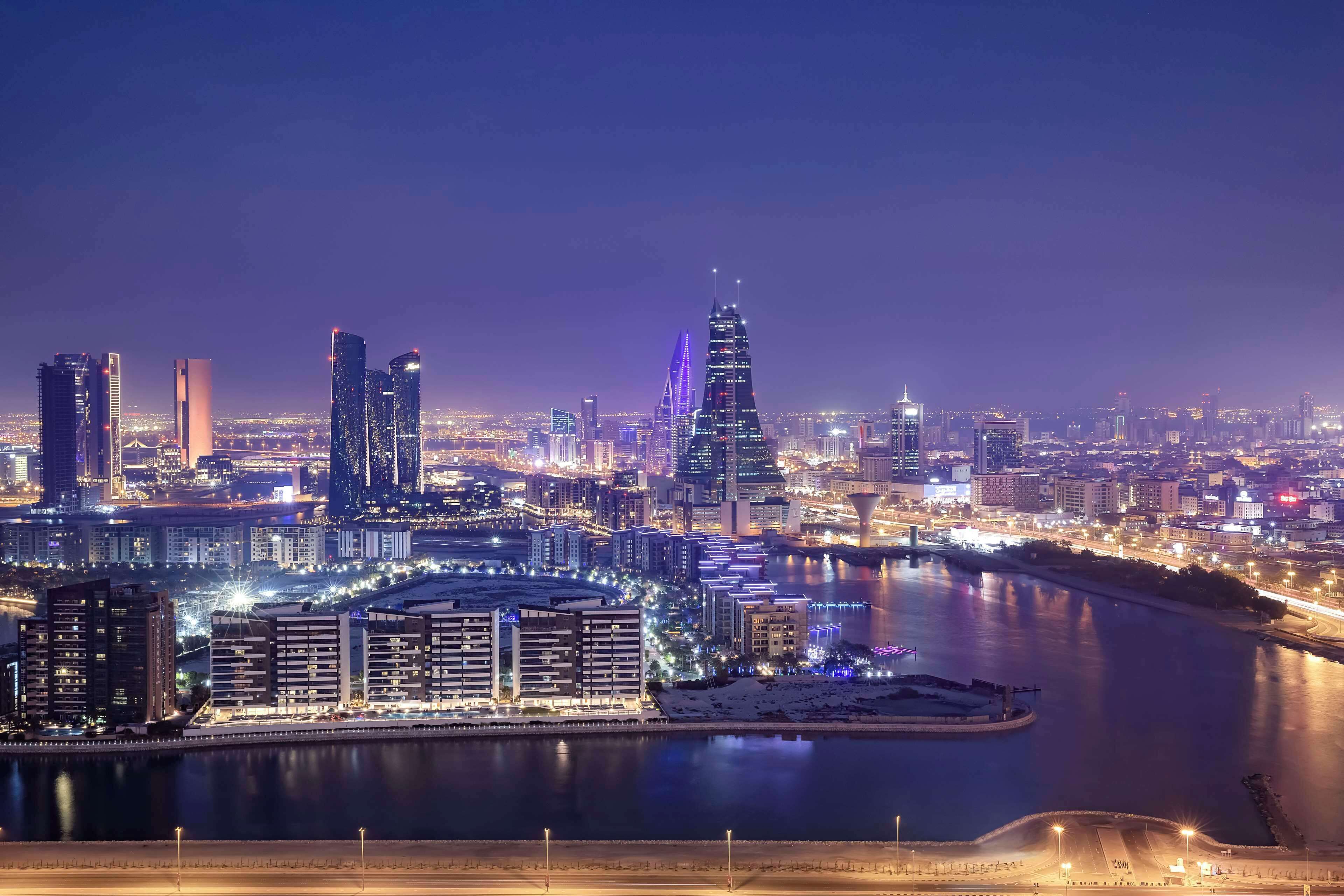 A nighttime cityscape with illuminated buildings and a river.