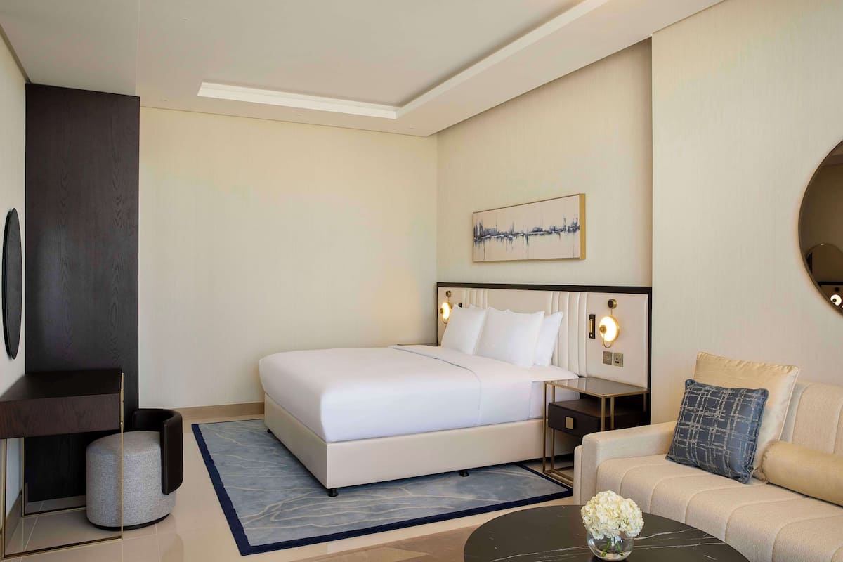 Una habitación de hotel moderna con una cama grande, un sofá, una mesa de centro y un televisor.