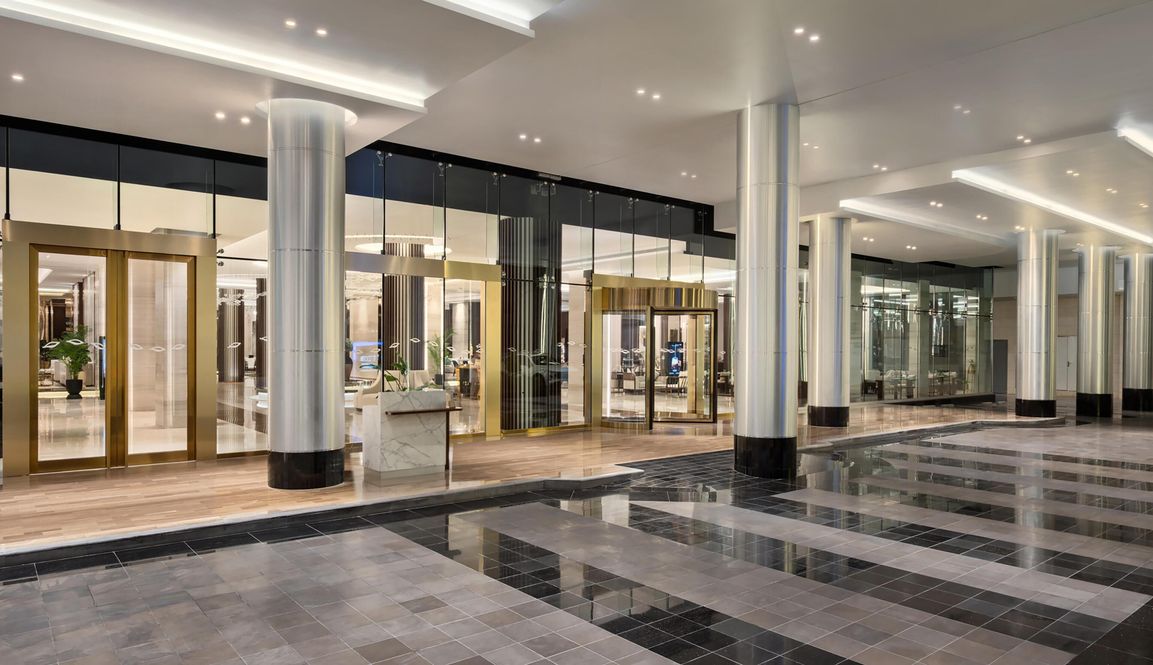 A spacious lobby with a marble floor, large glass doors, and modern lighting fixtures.