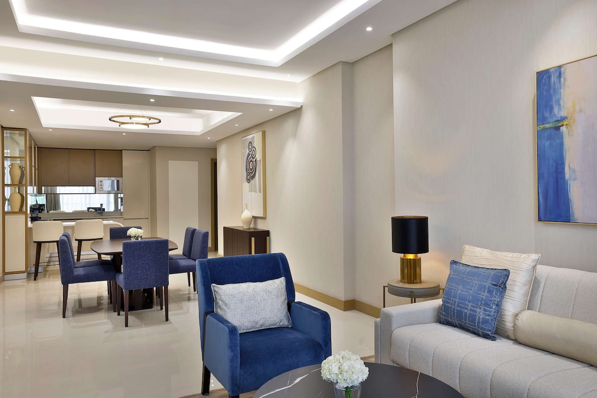 Una habitación de hotel moderna con zona de comedor, sofá y mesa de centro.