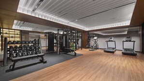 A modern gym with wooden flooring, weightlifting equipment, treadmills, and a bench. - Hilton Garden Inn Xi'An Bell Tower (Xi'an)