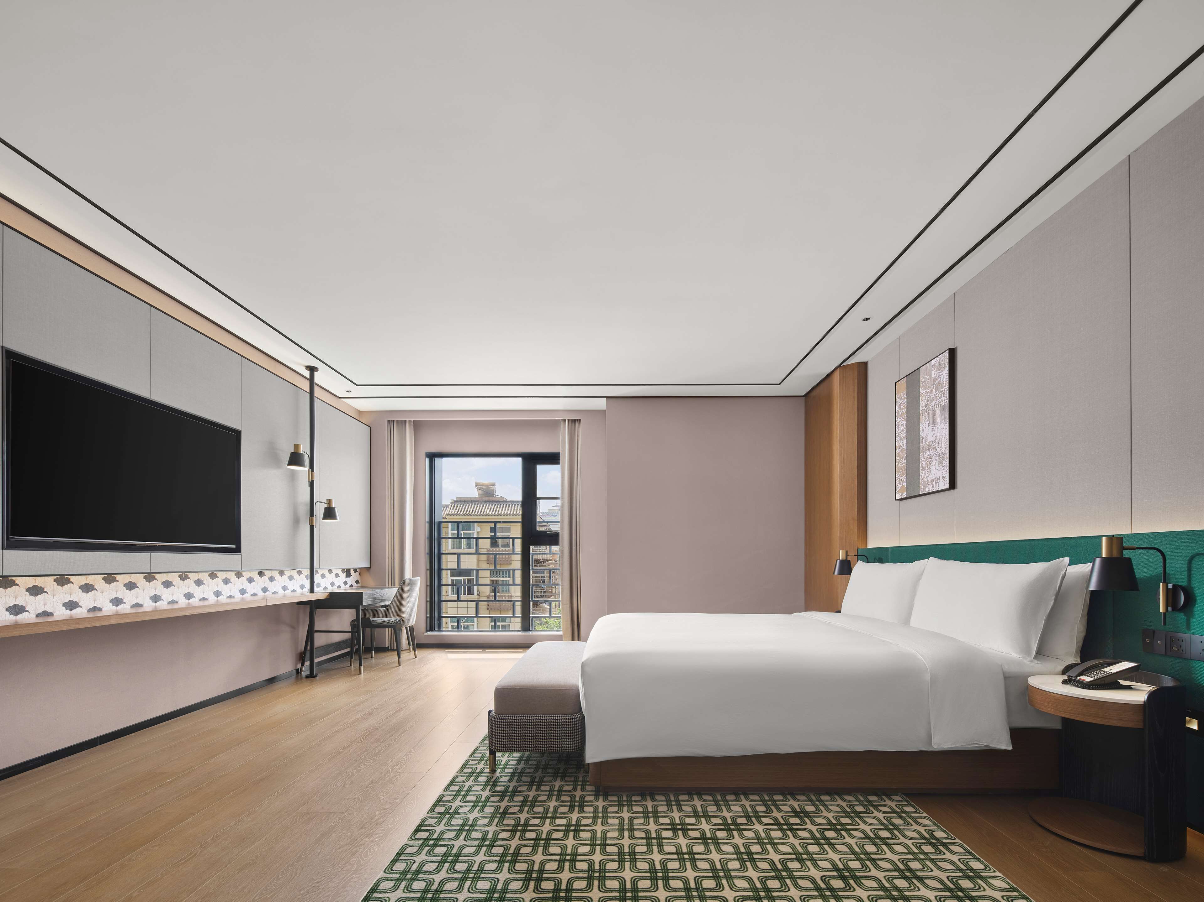 Quarto de hotel moderno com uma cama grande, uma escrivaninha e uma televisão.