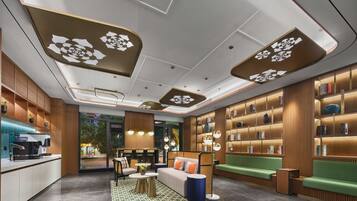 A modern hotel lobby with a reception desk, seating areas, and a bookshelf.