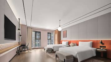 A modern hotel room with two beds, a desk, and a large TV.