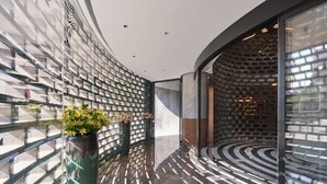 A modern interior with a curved glass wall, a patterned floor, and a brick wall with a circular design. - Hilton Garden Inn Xi'An Bell Tower (Xi'an)