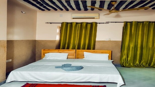 A single bed with a wooden headboard, white bedding, and a red rug. There is a ceiling fan and an air conditioning unit visible. - Charming 3-bedroom apartment in wonderful Zanzibar with AC, WiFi (Zanzibar)