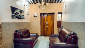 A lobby with two leather sofas, a wooden door, and a chandelier. - Charming 3-bedroom apartment in wonderful Zanzibar with AC, WiFi (Zanzibar)