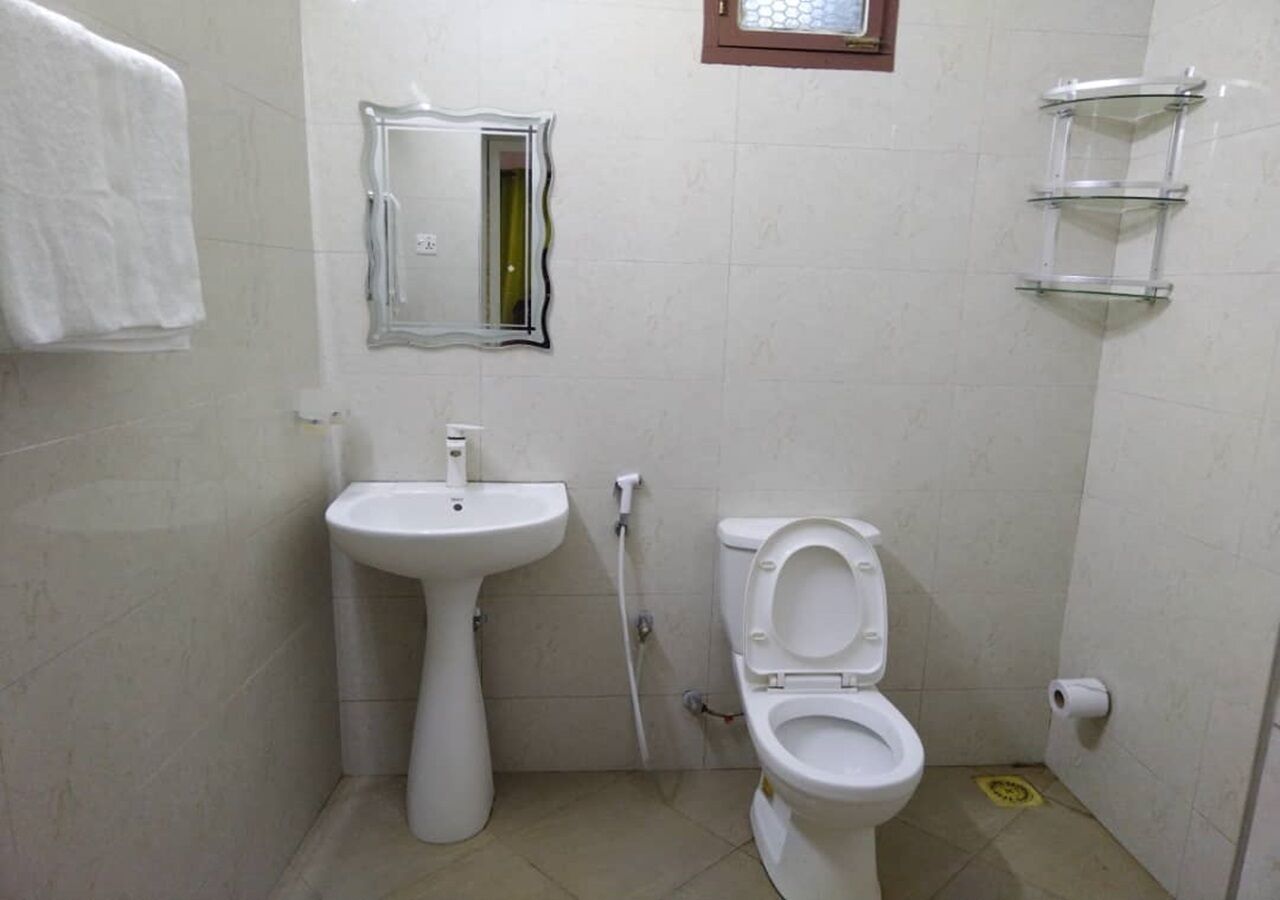Un baño pequeño con un lavamanos pedestal, un inodoro, un espejo y una toalla colgada en la pared.
