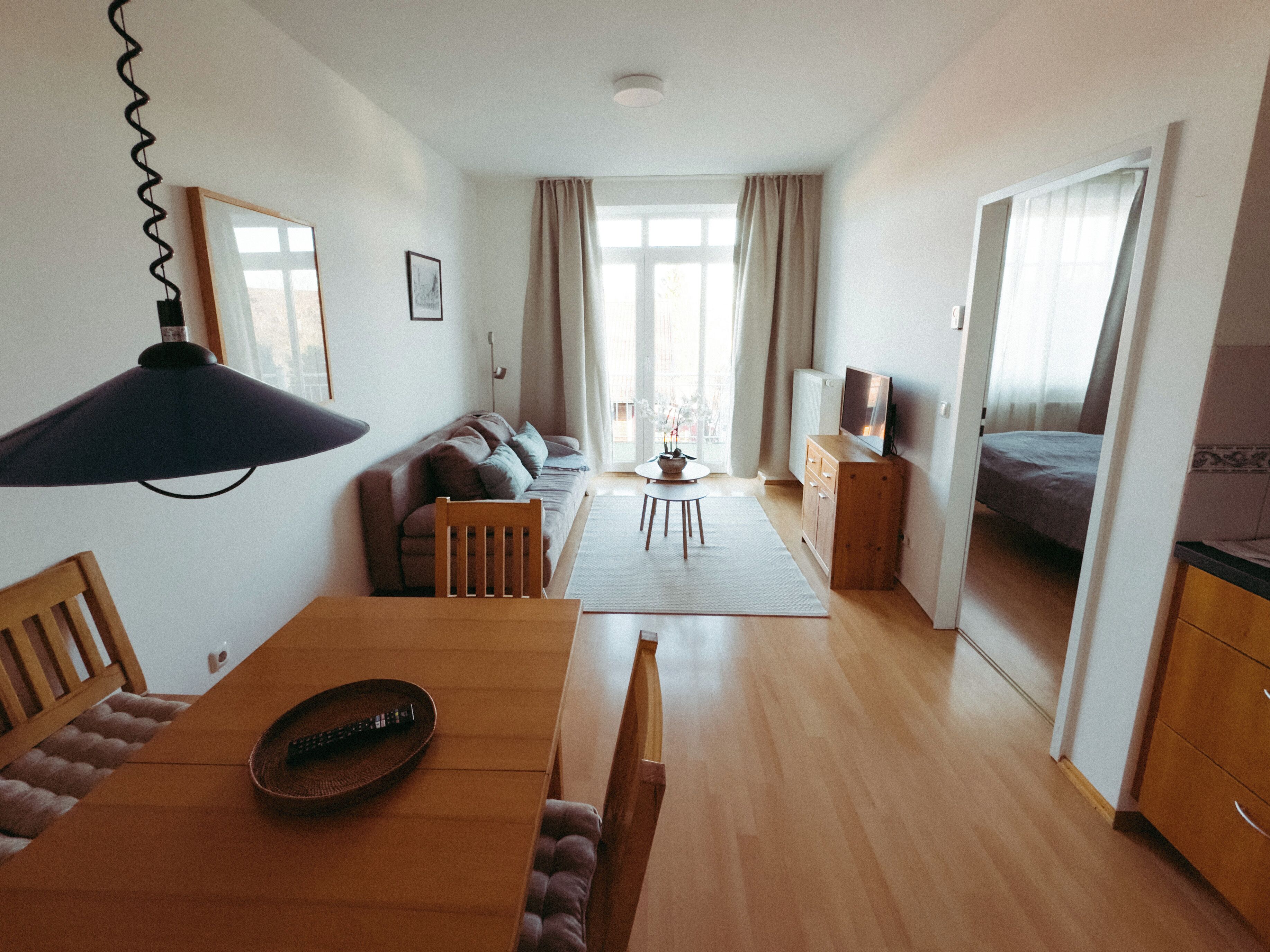 Un vaste espace de vie comprenant une table à manger, un canapé et un téléviseur posé sur un meuble en bois.
