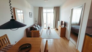 A spacious living area with a dining table, sofa, and a TV on a wooden cabinet. - Vacation apartment "Ammersee" at Andechs Monastery (Andechs)