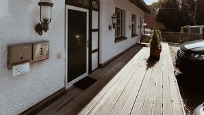 A building with a white exterior, a wooden deck, and a car parked nearby. - Vacation apartment "Ammersee" at Andechs Monastery (Andechs)