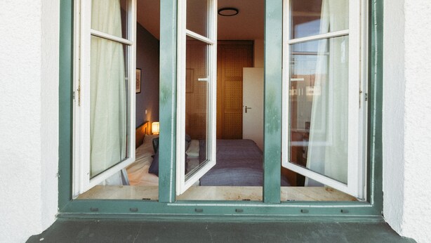 A doorway with a green frame leading to a room with a bed and a nightstand. - Vacation apartment "Ammersee" at Andechs Monastery (Andechs)