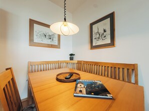 A dining area with a wooden table, chairs, a hanging light fixture, and two framed pictures on the wall. - Vacation apartment "Ammersee" at Andechs Monastery (Andechs)