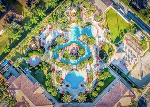 An aerial view of a resort with a central swimming pool, surrounded by palm trees and a parking area. - 4BR Home at Water Park Resort near Theme Parks (Davenport)