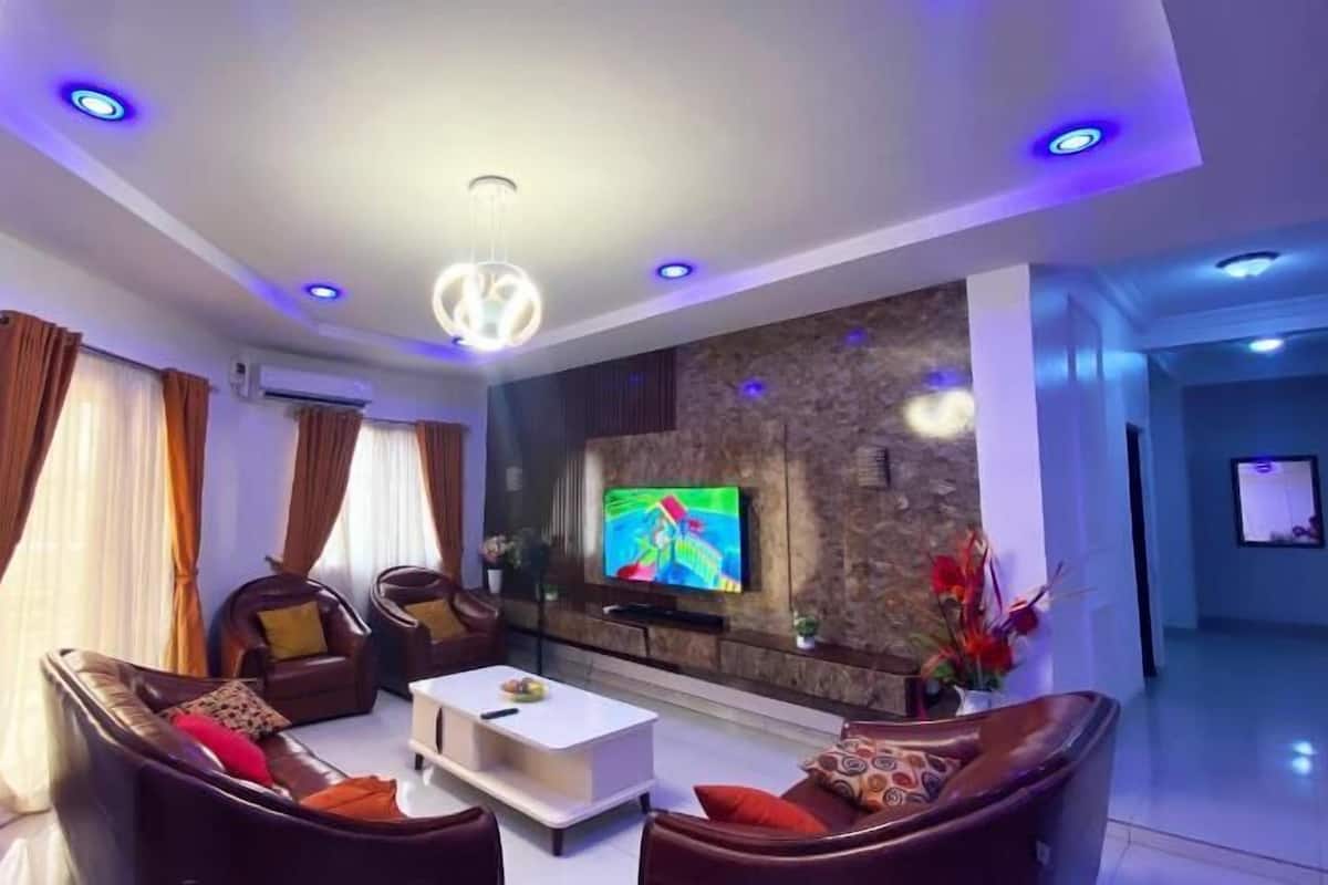A modern living room with a flat-screen TV, leather sofas, a coffee table, and a stone accent wall.