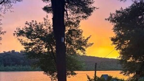 Une vue sur le lac, avec un coucher de soleil, des arbres et une jetée avec des chaises.