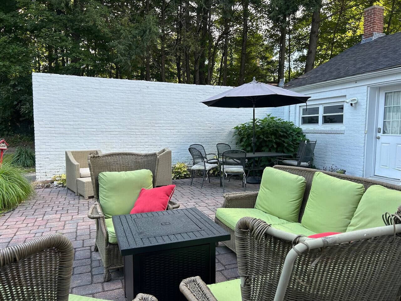 An outdoor patio area with wicker furniture, a table, and an umbrella.