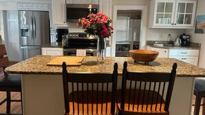 A kitchen with granite countertops, a stainless steel refrigerator, a microwave, and a wooden bowl on the island. - The Old Avon Village (Avon)