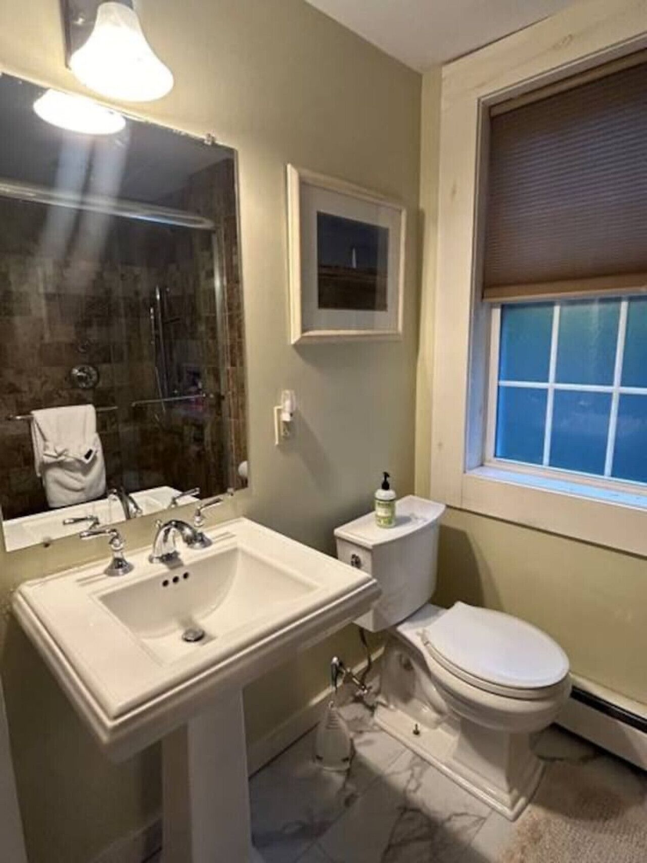 A bathroom with a sink, toilet, and a window with a view.