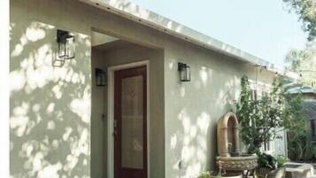 A house with a red door, a small porch, and a garden area with steps leading to the door.