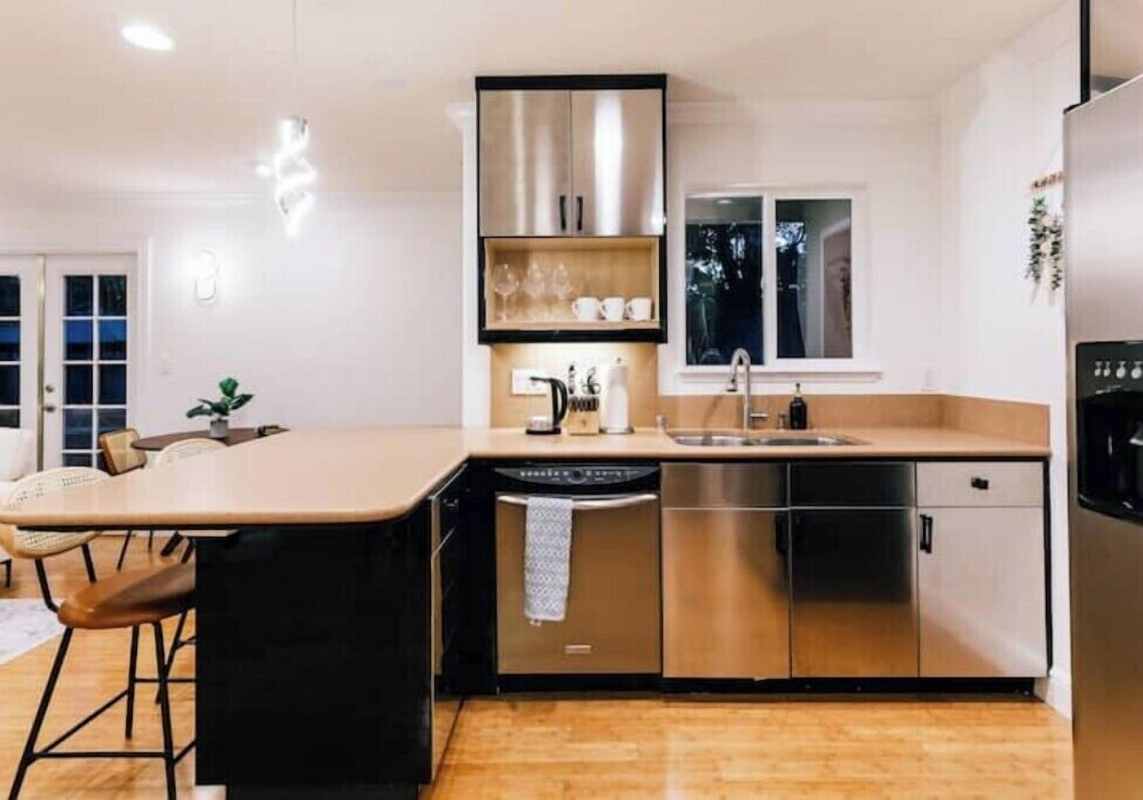 Una cocina moderna con electrodomésticos de acero inoxidable, lavavajillas integrado y un ventanal sobre el fregadero.