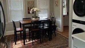Een eethoek met een tafel, stoelen, een vloerkleed en een hanglamp.