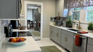 Een moderne keuken met een centraal eiland, een ingebouwde oven en een raam met decoratieve gordijnen.