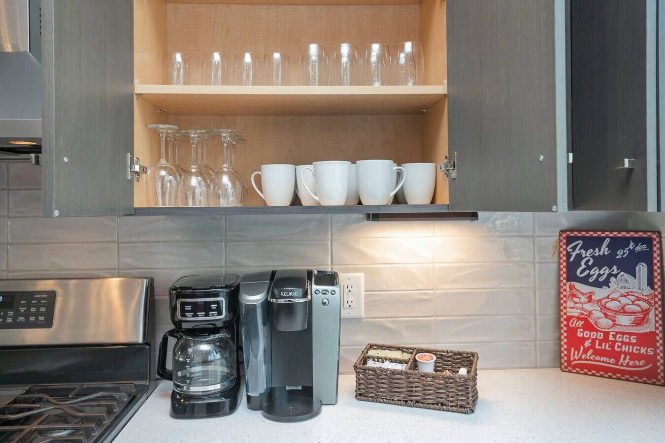 A kitchen with a coffee maker, a Keurig, a toaster, and a basket of bread.