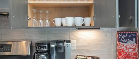 A kitchen with a coffee maker, a Keurig, a toaster, and a basket of bread.