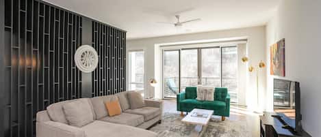 A modern living room with a sectional sofa, a green armchair, and a coffee table.