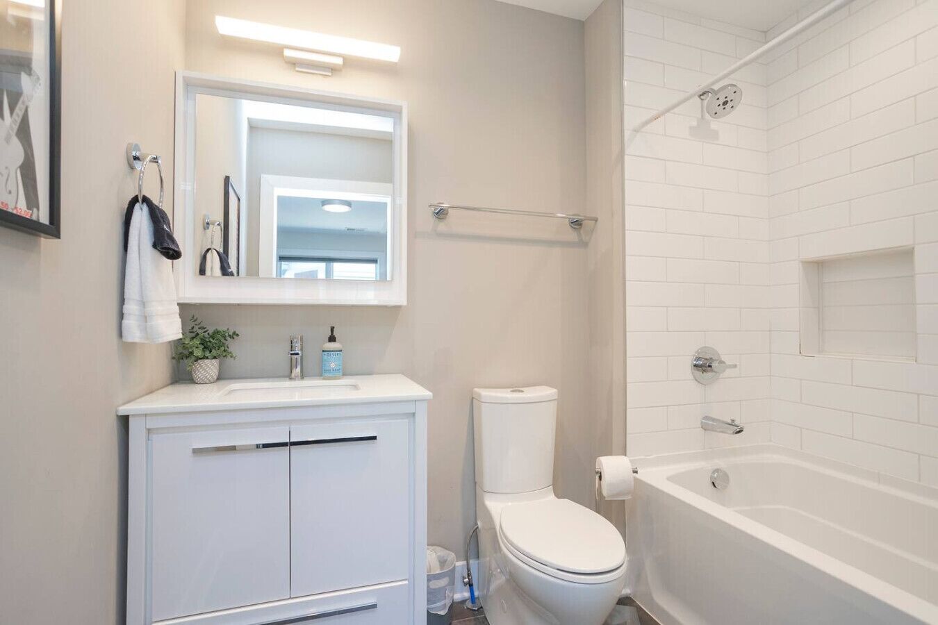 A bathroom with a white sink, mirror, and toilet. There is a shower area with a glass door and a bathtub.