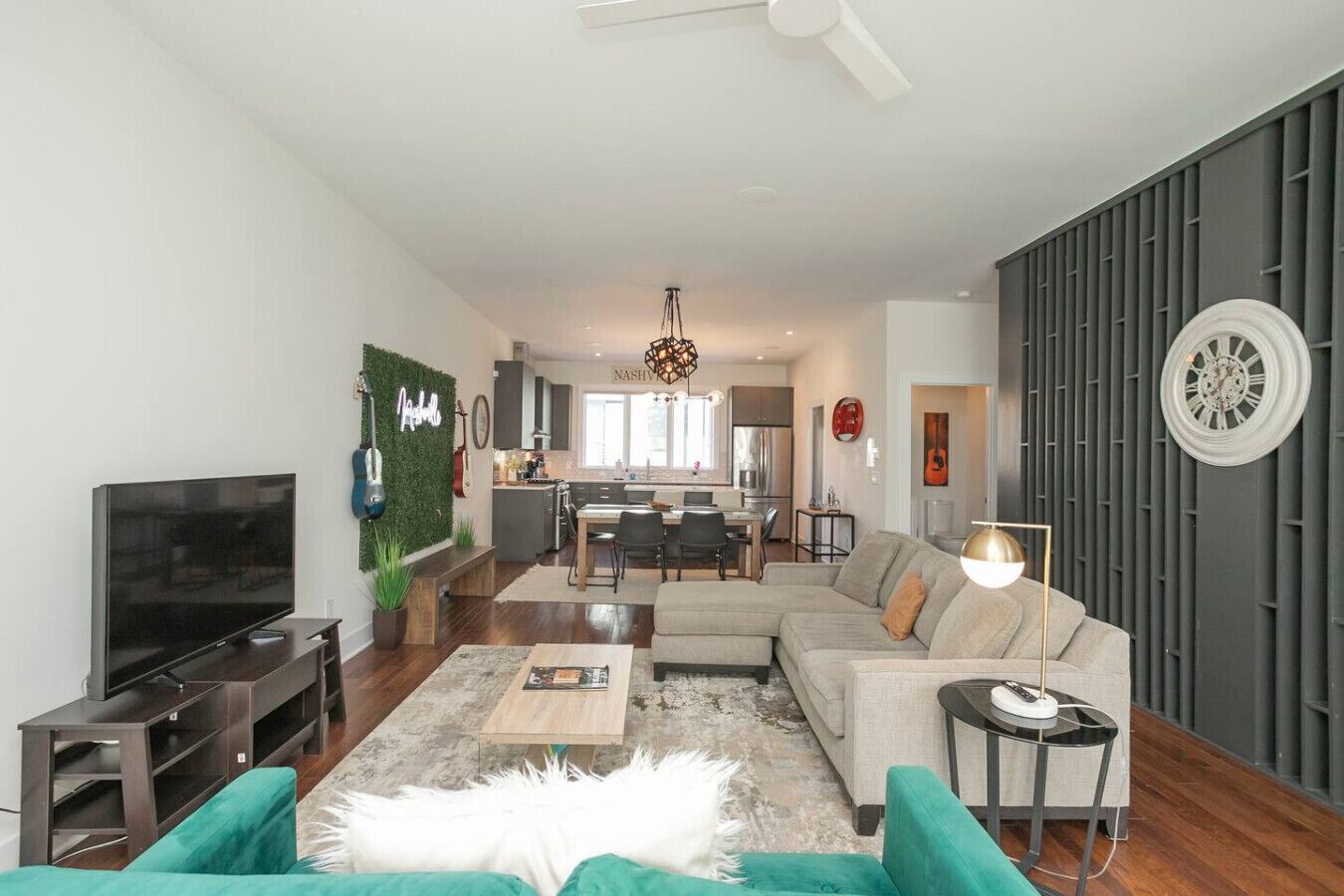 A modern living room with a flat-screen TV, a sofa, a coffee table, and a dining area in the background.