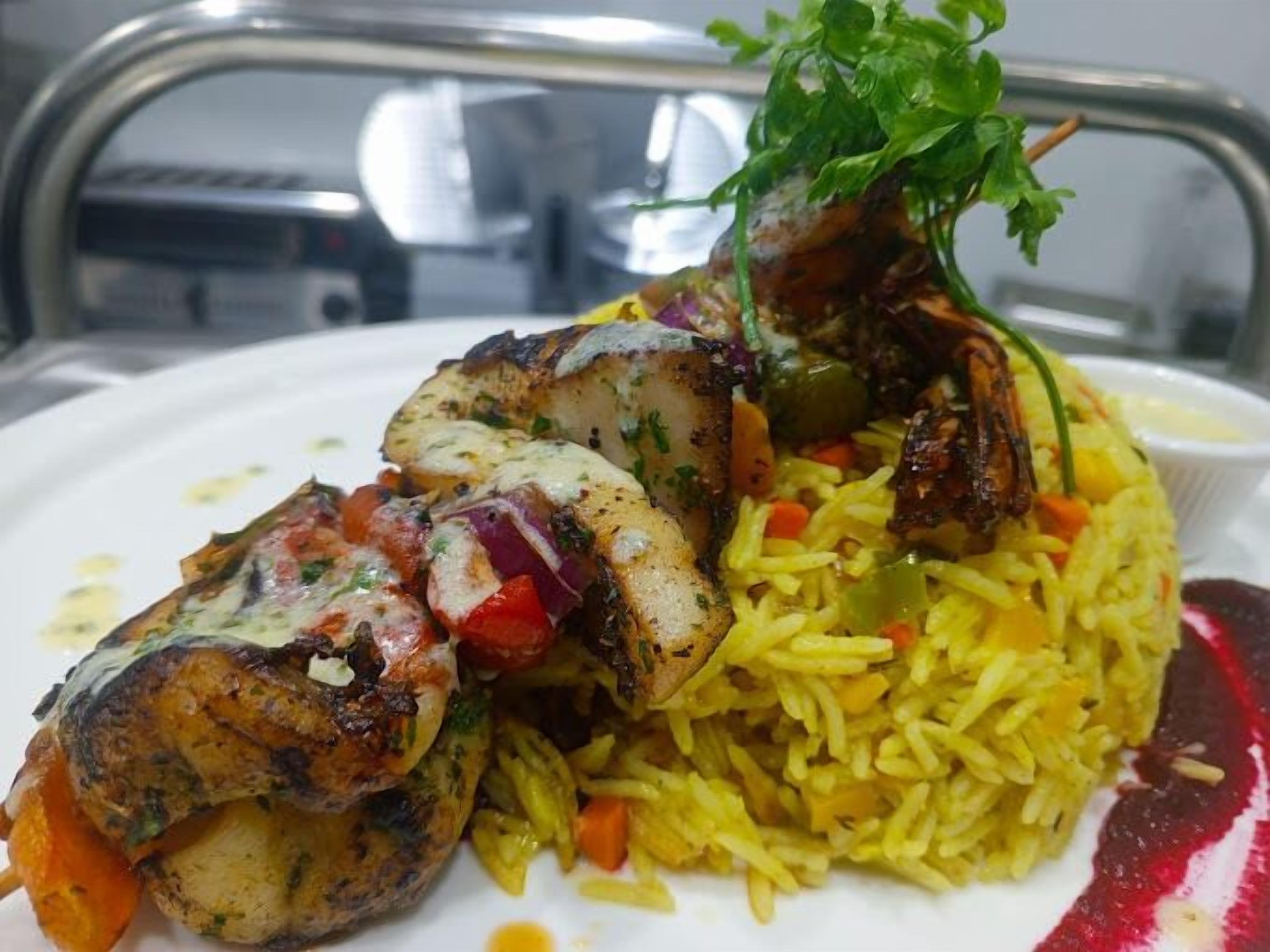 A plate of food with grilled chicken, rice, and vegetables.