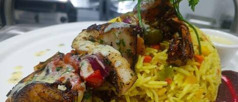 A plate of food with grilled chicken, rice, and vegetables.