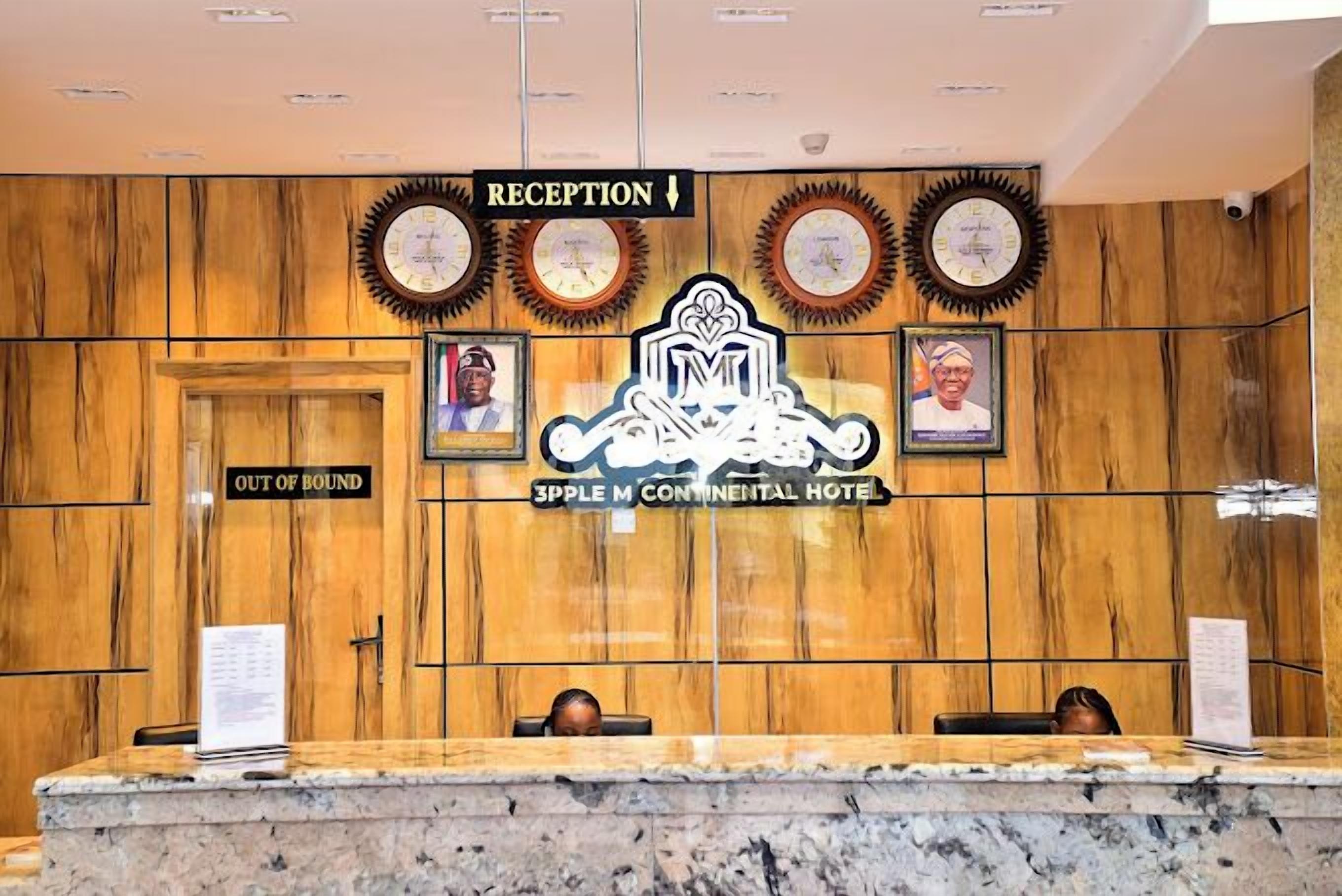 A reception area with a wooden panel wall, a marble reception desk, and framed photographs above the desk.