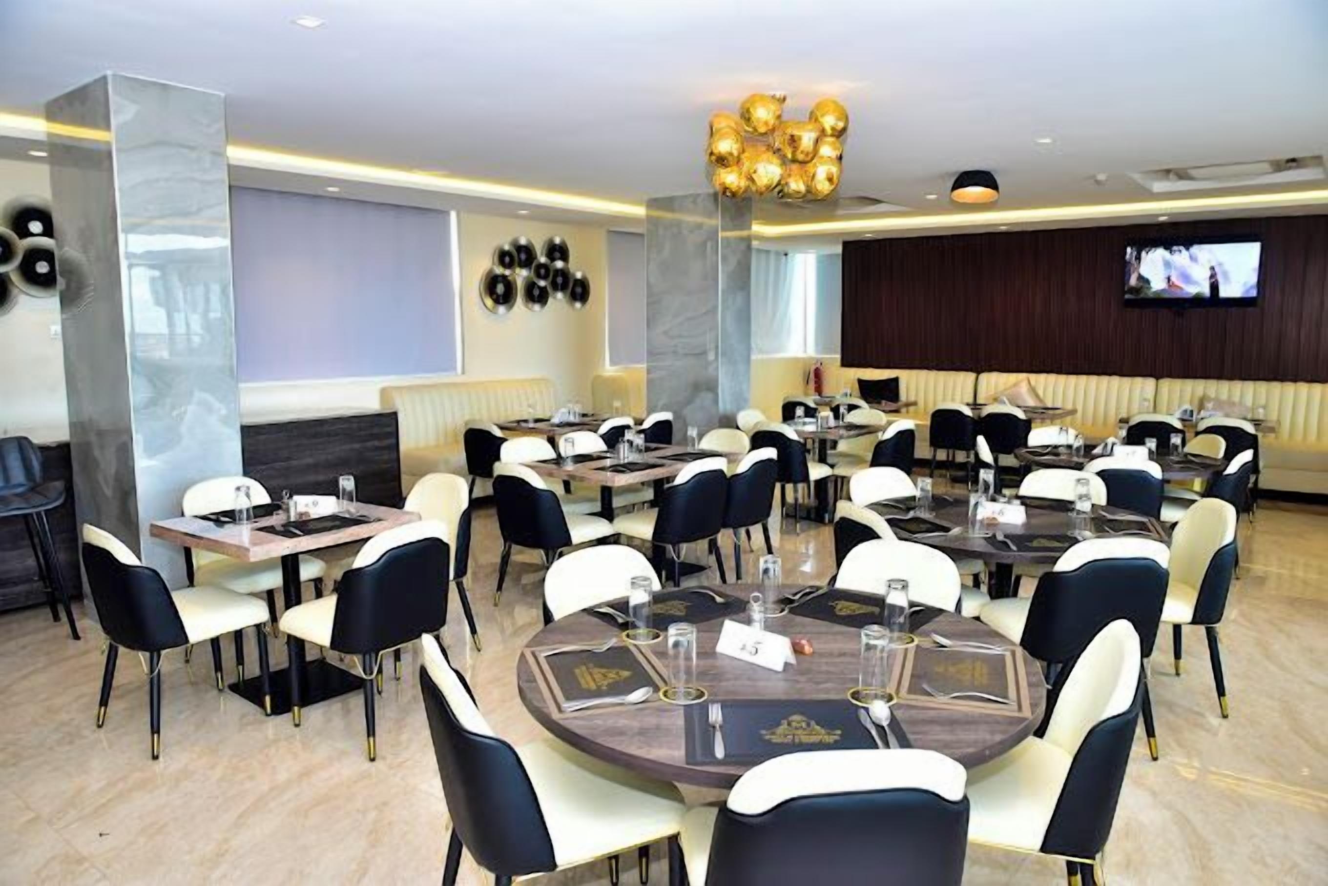 A conference room with round tables, black and white chairs, and a large chandelier.