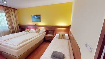 Habitación de hotel con dos camas, una mesita de noche, un cuadro en la pared y una ventana con cortinas.