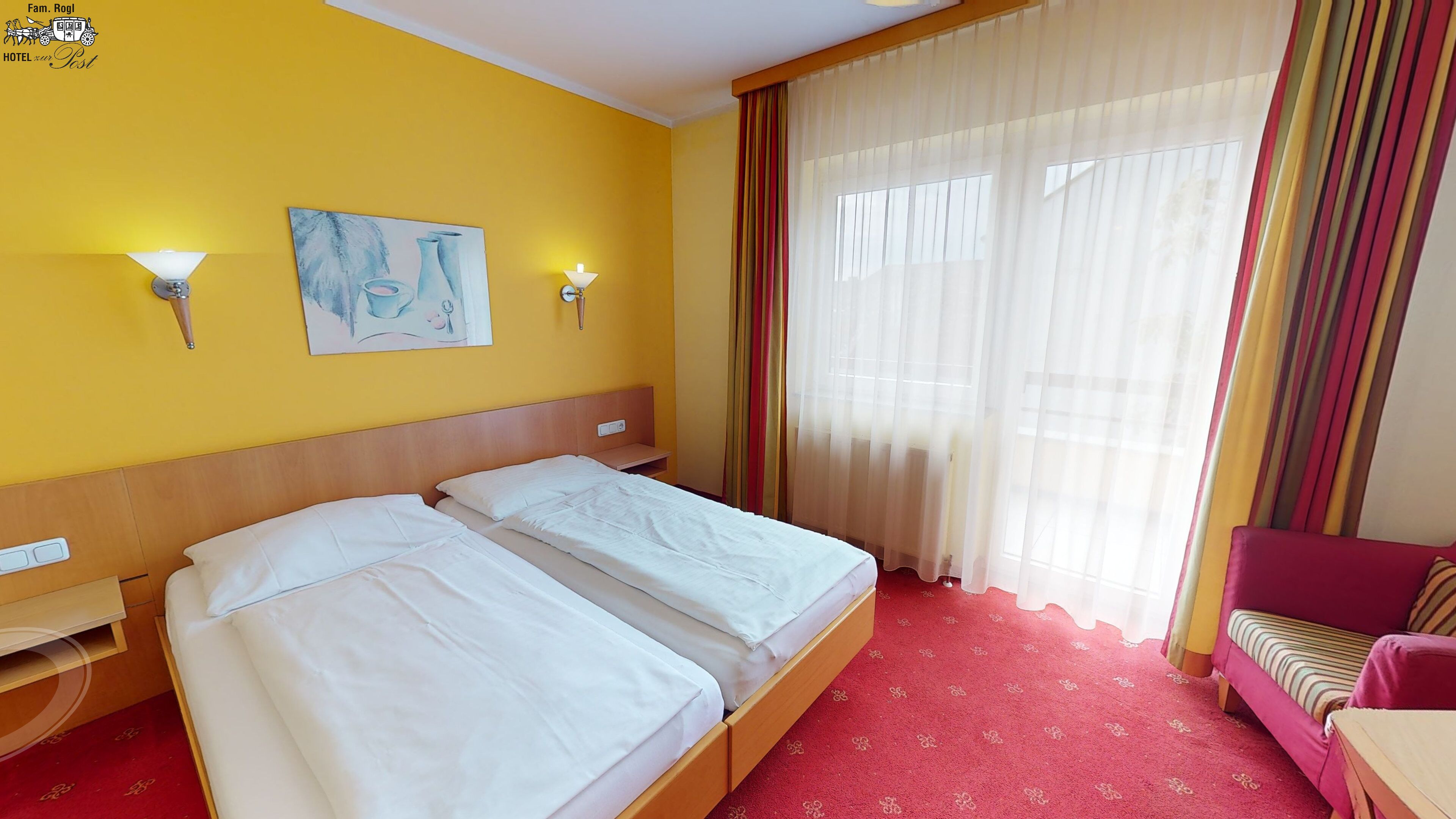 A hotel room with two beds, a red carpet, a red sofa, and a window with sheer curtains.