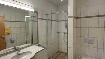 A modern bathroom with a glass-enclosed shower, a sink with a mirror, and a toilet.