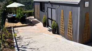 Ein Gebäude mit einer Schotterauffahrt, einer Terrasse und Gartenmöbeln sowie Kübelpflanzen.