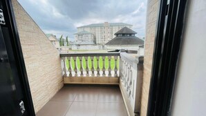 En utsikt från en balkong med ett klinkergolv och ett räcke, med utsikt över en byggnad med flera våningar och en tydlig arkitektonisk stil.