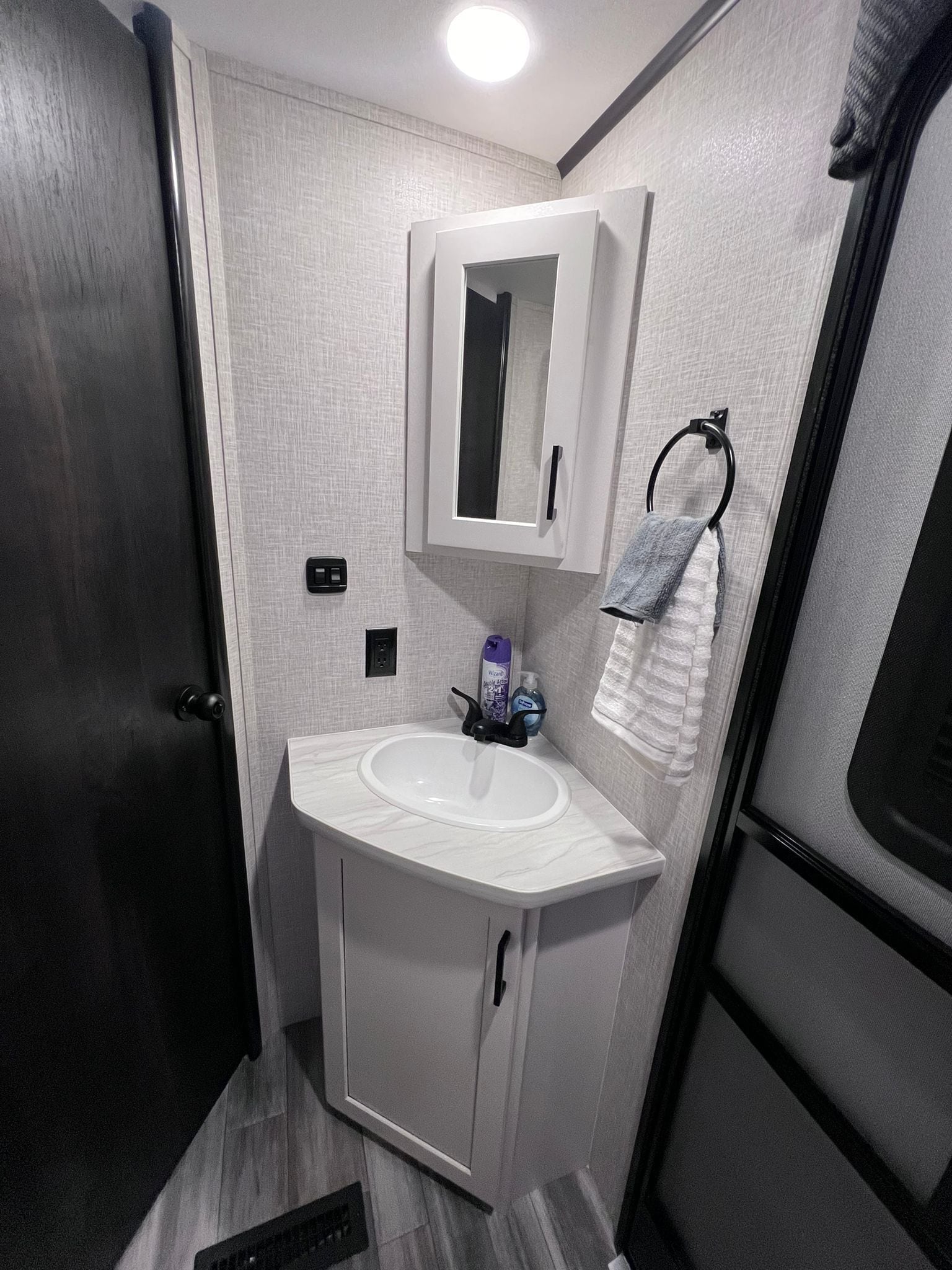Une petite salle de bain avec un lavabo blanc, un miroir au-dessus et une serviette suspendue à un porte-serviettes.