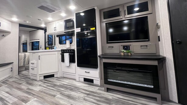 A compact kitchen with white cabinets, a microwave, a stove, and a large oven.