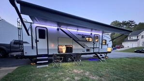 A recreational vehicle with a covered living area, a kitchen, and a sleeping area.