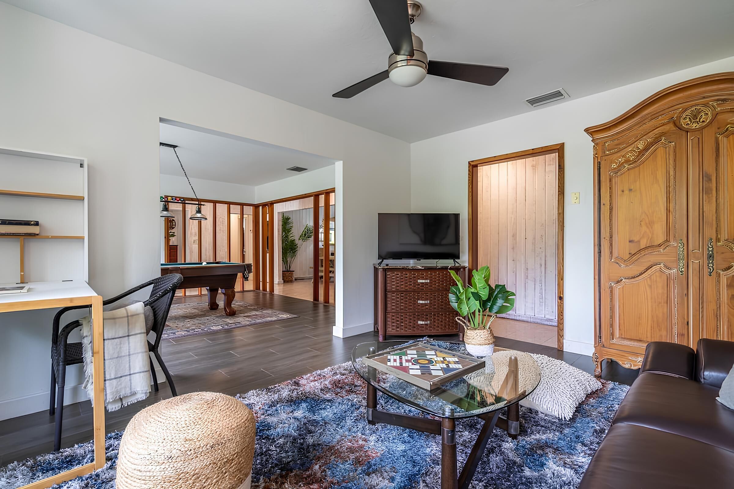 Un salon comprenant un canapé, une table basse, un téléviseur, un meuble en bois et un ventilateur de plafond.
