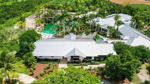 A large, modern house with a spacious patio, surrounded by lush greenery and a swimming pool. - Farmhouse Oasis Retreat in Homestead (Homestead)