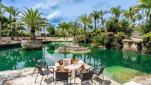 A pool area with a circular seating arrangement, surrounded by palm trees and greenery. - Farmhouse Oasis Retreat in Homestead (Homestead)
