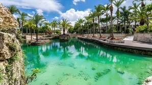 A pool area with clear water, surrounded by palm trees and a stone wall. - Farmhouse Oasis Retreat in Homestead (Homestead)