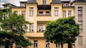 Un edificio amarillo con fachada simétrica, múltiples ventanas y un balcón central.