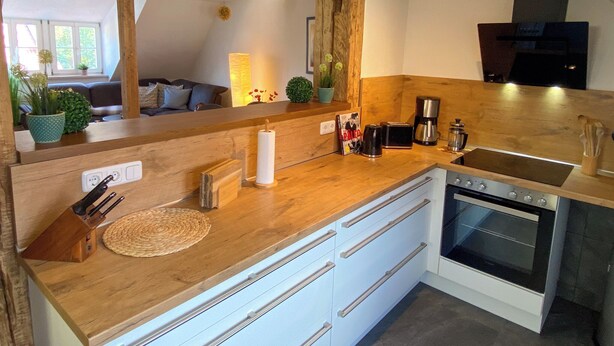 Una cocina con encimeras de madera, horno empotrado y un espejo grande.